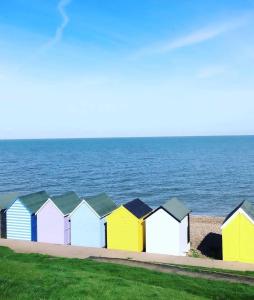 a row of colorful beach huts next to the ocean at Evening Tide in Herne Bay