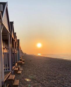 a sunset on the beach with a row of houses at Evening Tide in Herne Bay