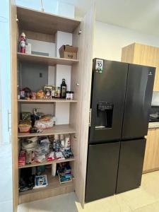 a kitchen with a refrigerator and shelves with food at Alojamiento entero en la Aurora. in Daule
