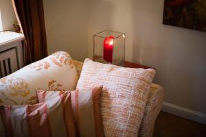 uma vela vermelha numa mesa ao lado de um sofá com almofadas em Klingler s Hues App 1 em Wenningstedt