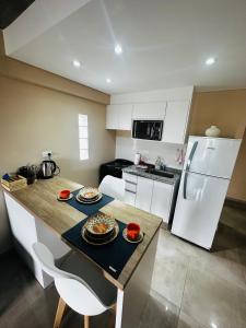 eine Küche mit einem Tisch und einem weißen Kühlschrank in der Unterkunft Park Garden Tucumán in San Miguel de Tucumán