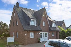 uma grande casa de tijolos vermelhos com um telhado preto em Feriendomizil App 5 em Wenningstedt