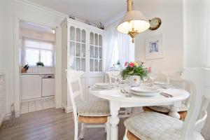 uma sala de jantar branca com uma mesa e cadeiras brancas em Feriendomizil App 5 em Wenningstedt
