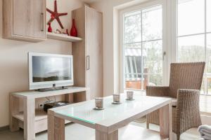 uma sala de estar com uma mesa e uma televisão em Feriendomizil App 1 em Wenningstedt