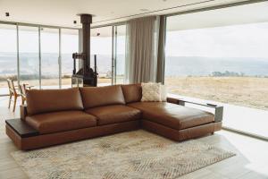 un divano in pelle marrone in un soggiorno con una grande finestra di The Cloud at Sen Vineyard a White Hills