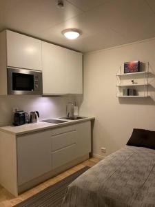 a kitchen with white cabinets and a bed in a room at Modern studio apartment in fantastic nature in Tromsø