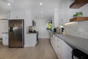 a kitchen with white cabinets and a stainless steel refrigerator at Venice Villa with pool, music studio in Los Angeles