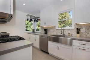 uma cozinha com armários brancos e um lavatório de aço inoxidável em Venice Villa with pool, music studio em Los Angeles