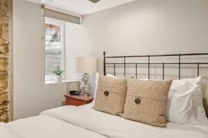 a bedroom with a bed with white sheets and pillows at Garden Apartment - Decor Upgrades - Capitol Hill in Denver