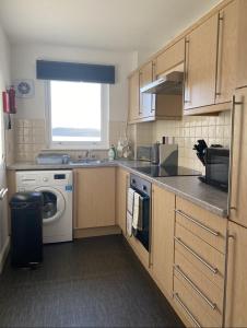 a kitchen with a sink and a washing machine at Prime Dalgety Bay Waterfront Apartment in Saint Davids