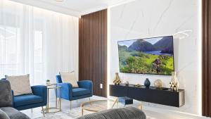 een woonkamer met twee blauwe stoelen en een televisie bij Champions Gate 6br Cozy Home With Pool Spa 8927 in Orlando