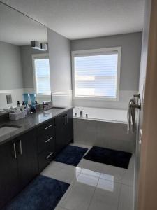 uma casa de banho com um lavatório, uma banheira e uma janela em Cozy Gems of Kensington em Calgary
