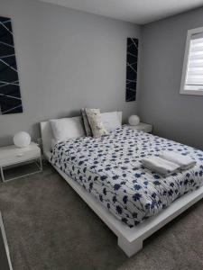 a bedroom with a bed with a blue and white comforter at Cozy Gems of Kensington in Calgary