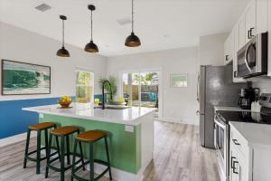 una cocina con armarios blancos y una isla verde con taburetes. en Magic Hour, en St. Augustine