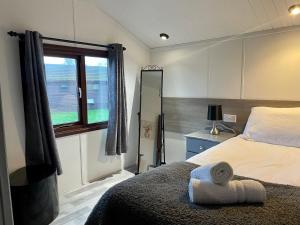 a bedroom with a large bed and a window at Cosy 3 Bed Lodge in Hoburne, Cotswolds in South Cerney