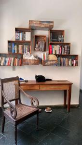 a black cat laying on a wooden desk next to a chair at Casa Nonada in São João del Rei