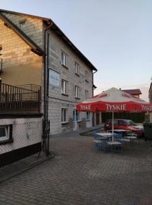 un patio con mesas y sombrillas frente a un edificio en Pokoje Goscinne Buzuki en Ciechanów