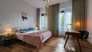a bedroom with a bed and a desk and windows at Innenstadt Studio in Pforzheim