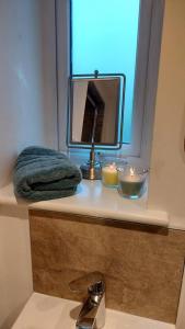 Ein Badezimmerwaschbecken mit Spiegel und Kerzen auf einer Ablage in der Unterkunft 1 Bed Flat - Sleeps 4 - Garden - Parking - Wifi in Hawkshead