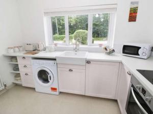 a white kitchen with a sink and a washing machine at The Cottage in Baxterley. Peaceful home from home. Beautifully finished. in Baxterley