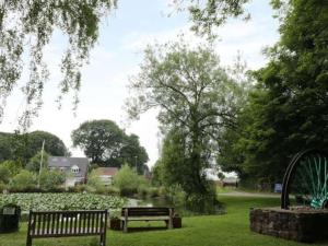 a park with two benches and a pond in the grass at The Cottage in Baxterley. Peaceful home from home. Beautifully finished. in Baxterley
