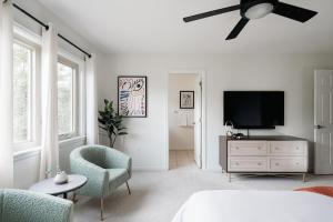 een witte slaapkamer met een plafondventilator en een televisie bij Golden Foothills - Hot Tub - Hiking & Biking! in Golden