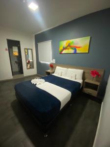 a bedroom with a large bed with blue and white sheets at Hotel America 52 in Rionegro