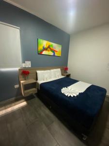 a bedroom with a large bed with a blue blanket at Hotel America 52 in Rionegro