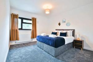 a bedroom with a bed with blue sheets and a window at Eco Home for Large Groups w/ FREE Parking & Wi-Fi in Bristol