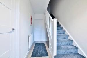 una escalera con moqueta azul, paredes blancas y escaleras blancas en Eco Home for Large Groups w/ FREE Parking & Wi-Fi en Bristol