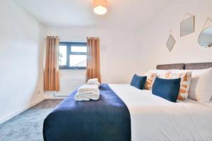 a bedroom with a large white bed with blue pillows at Eco Home for Large Groups w/ FREE Parking & Wi-Fi in Bristol