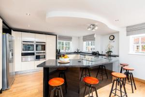 a kitchen with a large island with orange bar stools at Oak Cottage, HS2, NEC, BHX, M42, Family Gatherings, Contractors, Relocators in Birmingham
