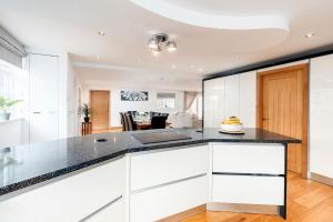 a kitchen with white cabinets and a black counter top at Oak Cottage, HS2, NEC, BHX, M42, Family Gatherings, Contractors, Relocators in Birmingham