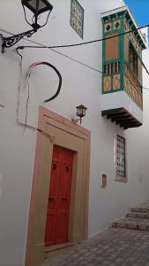 un bâtiment blanc avec une porte rouge et un éclairage de rue dans l'établissement Dar Baaziz 3, à Sousse