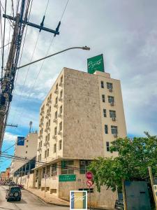 a tall building on a city street with a street sign at Hotel Oscar Econômico Montes Claros in Montes Claros