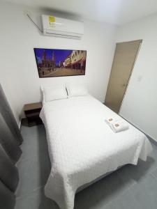 1 dormitorio con 1 cama blanca con manta blanca en CASA HOTEL YEMI, en Barranquilla