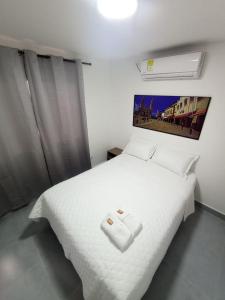 een slaapkamer met een wit bed en een witte deken bij CASA HOTEL YEMI in Barranquilla
