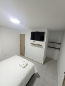 a white bedroom with a bed and a flat screen tv at CASA HOTEL YEMI in Barranquilla