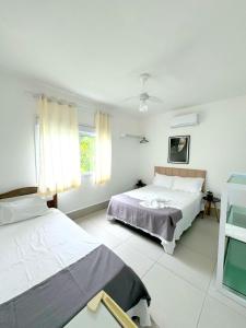 a white room with two beds and a window at Pousada Village Cozumel in Guarujá +89 photos