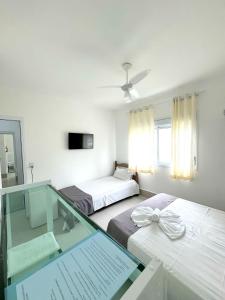 a room with two beds and a glass table at Pousada Village Cozumel in Guarujá