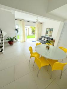 a living room with a white table and yellow chairs at Pousada Village Cozumel in Guarujá
