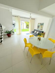 a living room with a white table and yellow chairs at Pousada Village Cozumel in Guarujá +88 photos