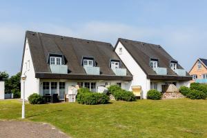 ein großes weißes Haus mit schwarzem Dach in der Unterkunft Landhaus Westerhörn, Sölring Tir, App. 1 in Wenningstedt-Braderup