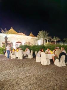 a group of people sitting at tables at night at Desert Rose Camp in Bidiyah