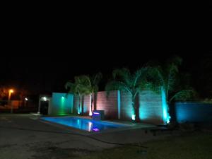a swimming pool at night with blue and green lights at Finca La Fortaleza zanjon in Santiago del Estero