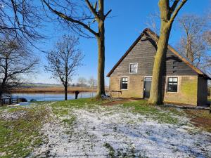 een oud huis met twee bomen naast een meer bij Picturesque Holiday Home in Drimmelen with Garden in Hooge Zwaluwe