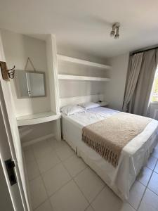 a white bedroom with a bed and a mirror at Apê na Gávea in Rio de Janeiro