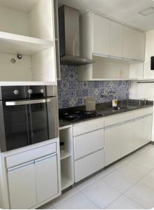 uma cozinha com armários brancos e um forno com placa de fogão em Apê na Gávea no Rio de Janeiro