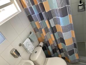 a bathroom with a toilet and a shower curtain at Acogedor y confortable miniapartamento in Los Ángeles