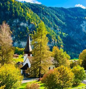 a church in the middle of a field with trees at Chalet Rosa B&B in Lauterbrunnen